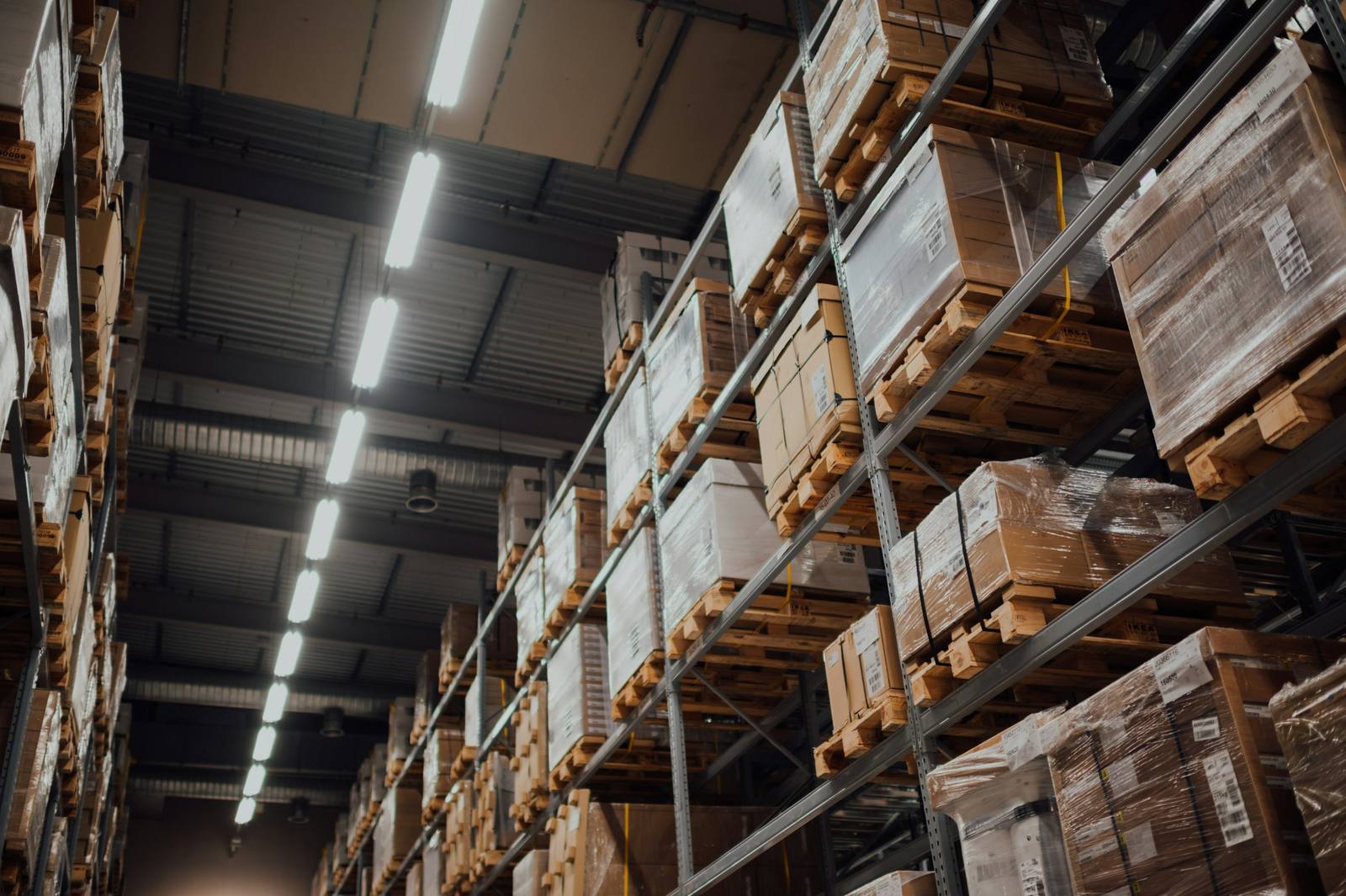 Warehouse aisle with tall racks of shrink-wrapped boxes on pallets